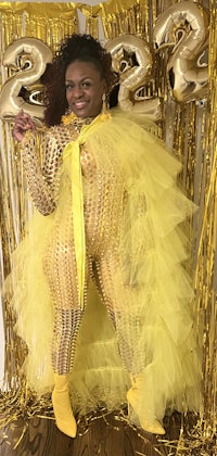 a woman in a yellow tulle outfit posing in front of balloons