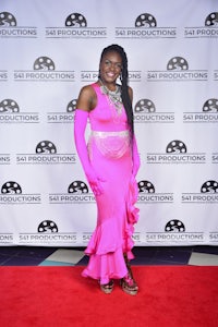 a woman in a pink dress standing on a red carpet